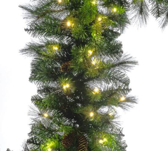 Artificial Christmas tree with lights and pinecones on a white background
